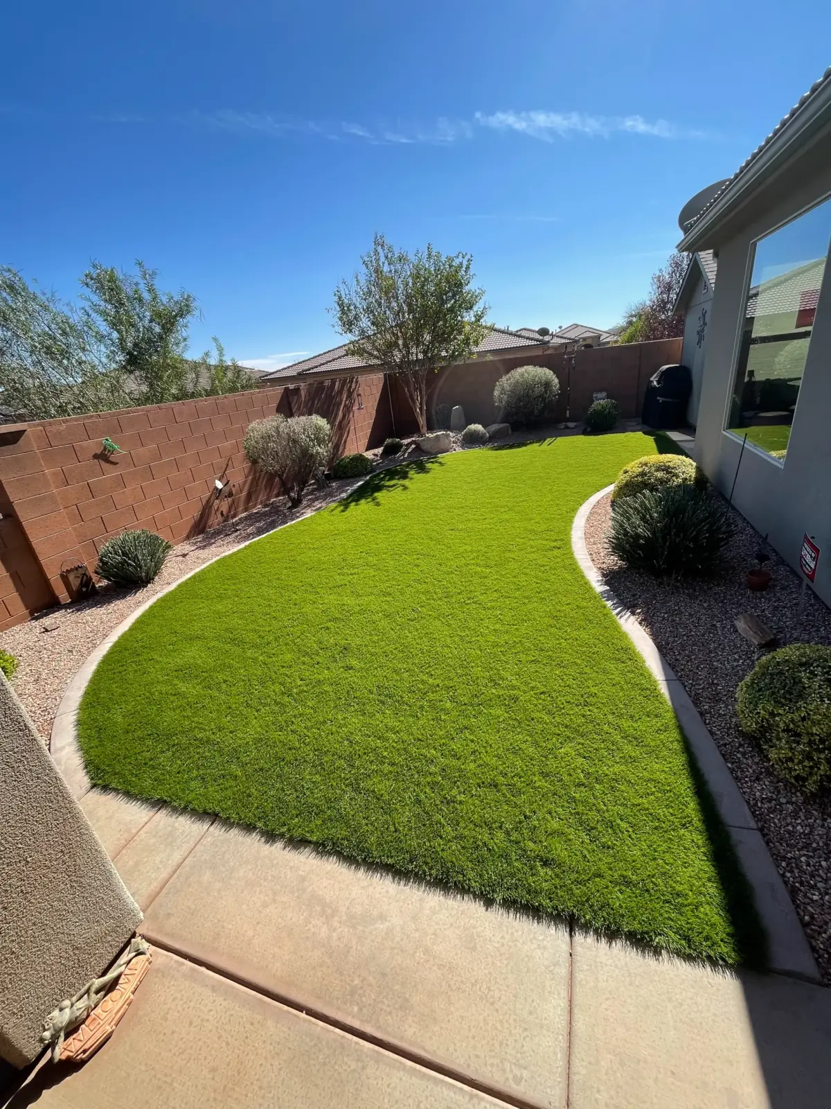 Backyard turf with curved curbing along a block wall