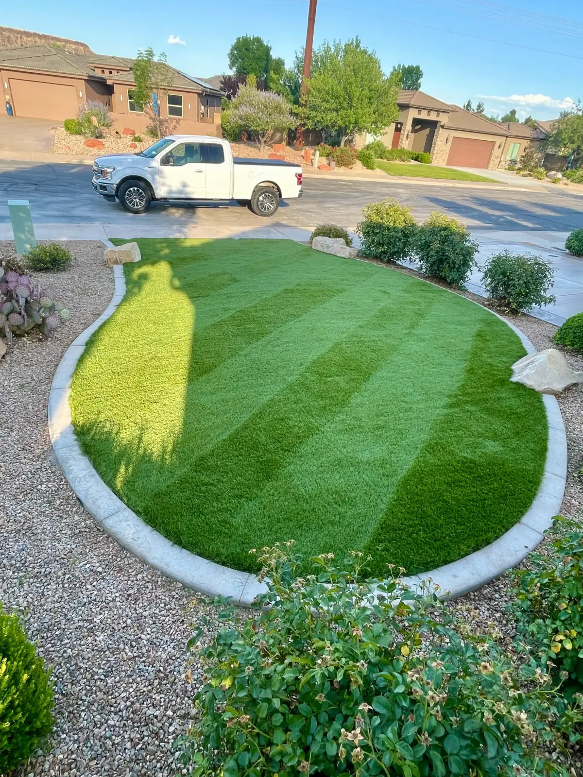 Striped artificial turf front lawn with curved concrete border